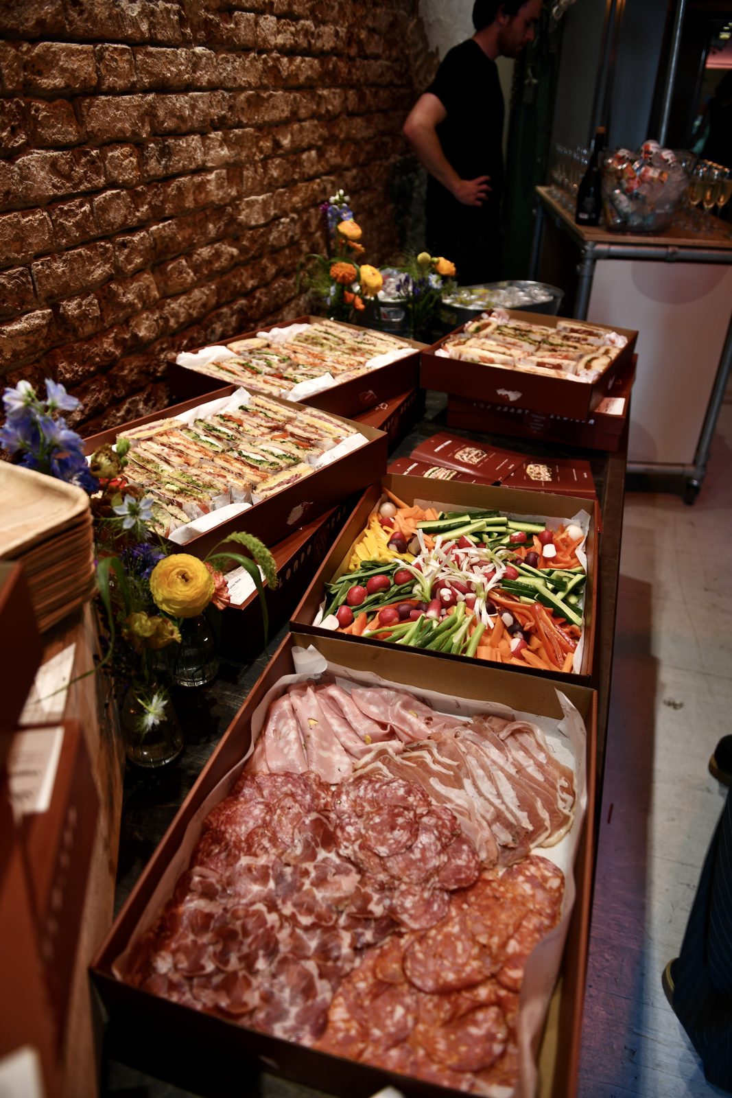 Santo Cielo spread at the Bio and Me event with sandwich platters, crudites and charcuterie against a brick wall