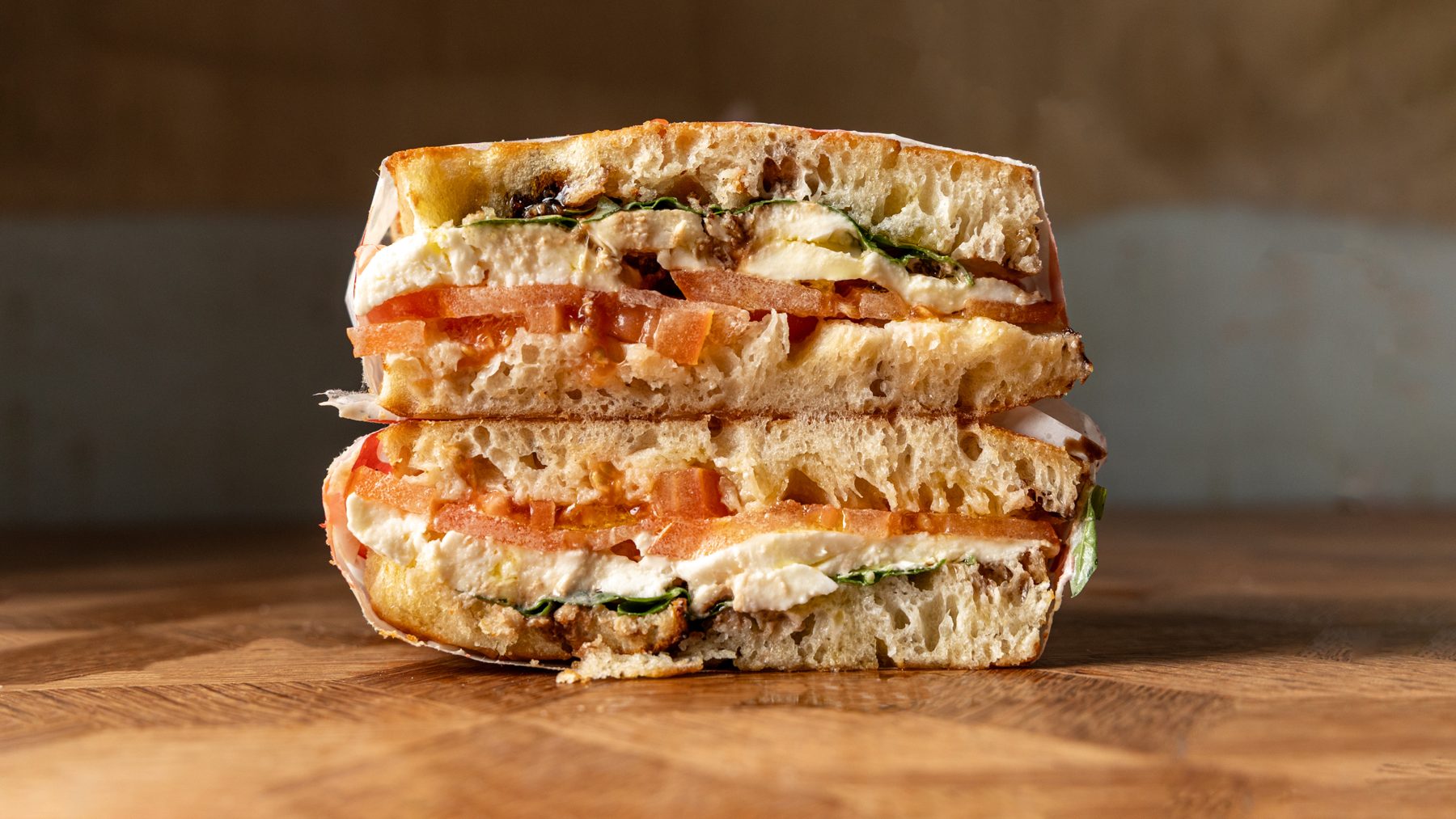 The Capri Caprese schiacciata cut in half showing fior di latte mozzarella, beef tomatoes and fresh basil