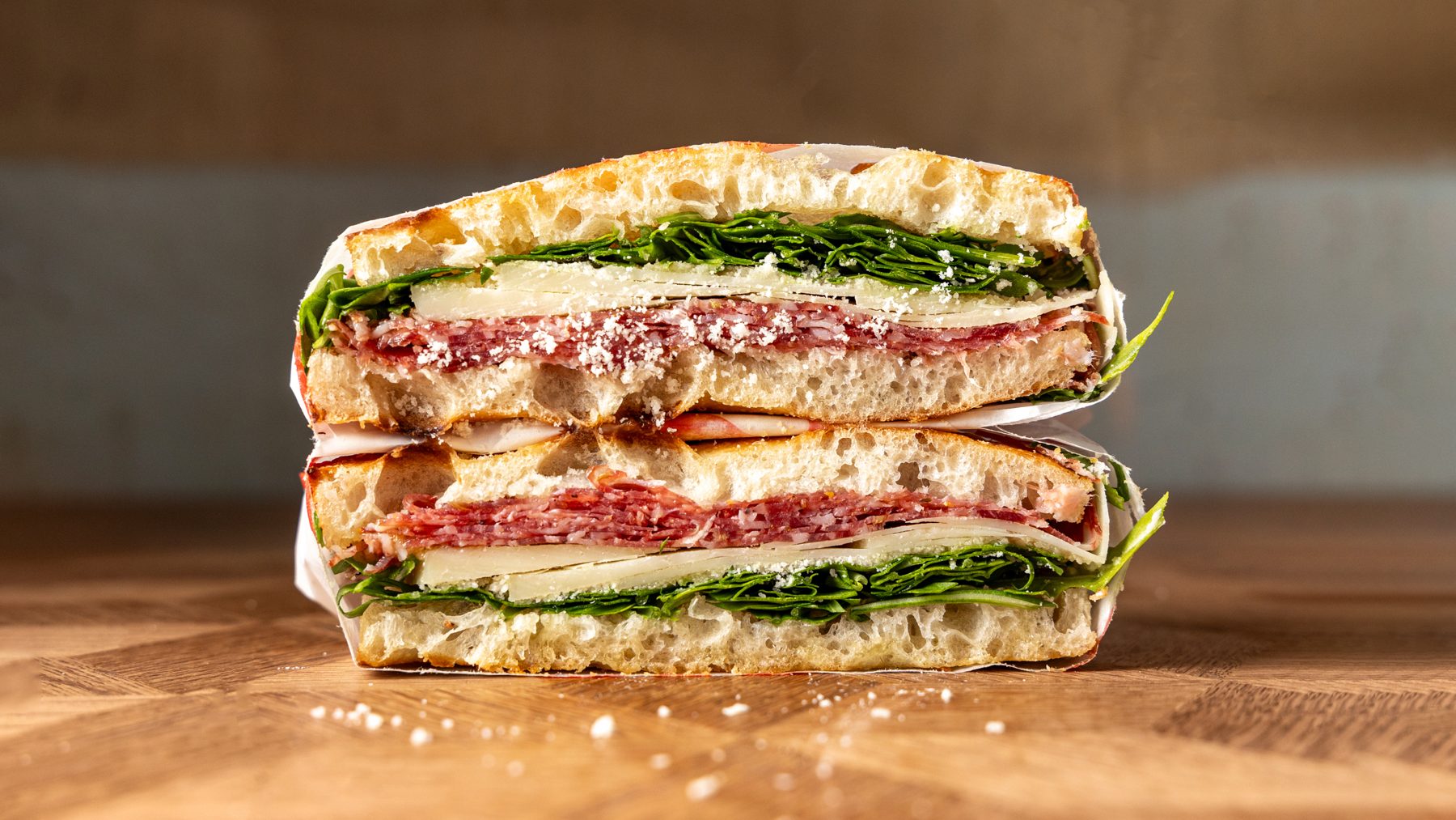 The Dal Firenze schiacciata cut in half showing fennel salami, provolone, pecorino shavings and rocket on Tuscan bread