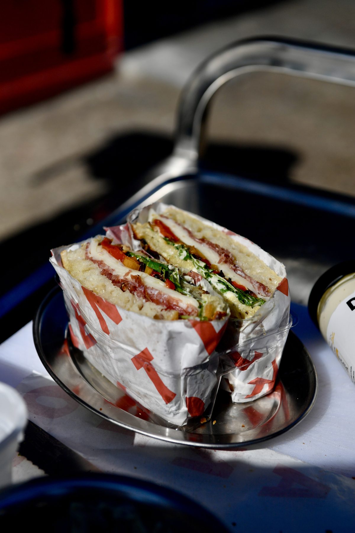 The Il Dotori schiacciata in Santo Cielo wrapping on a metal tray, showing fennel salami, provolone, roasted peppers and rocket