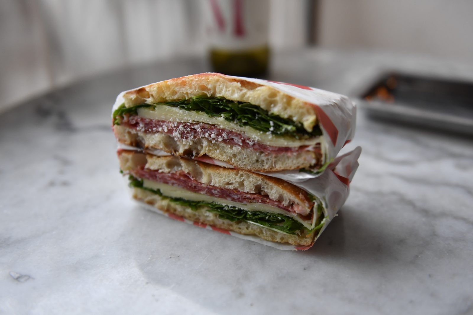 An individually wrapped Santo Cielo schiacciata half in branded paper on a marble counter