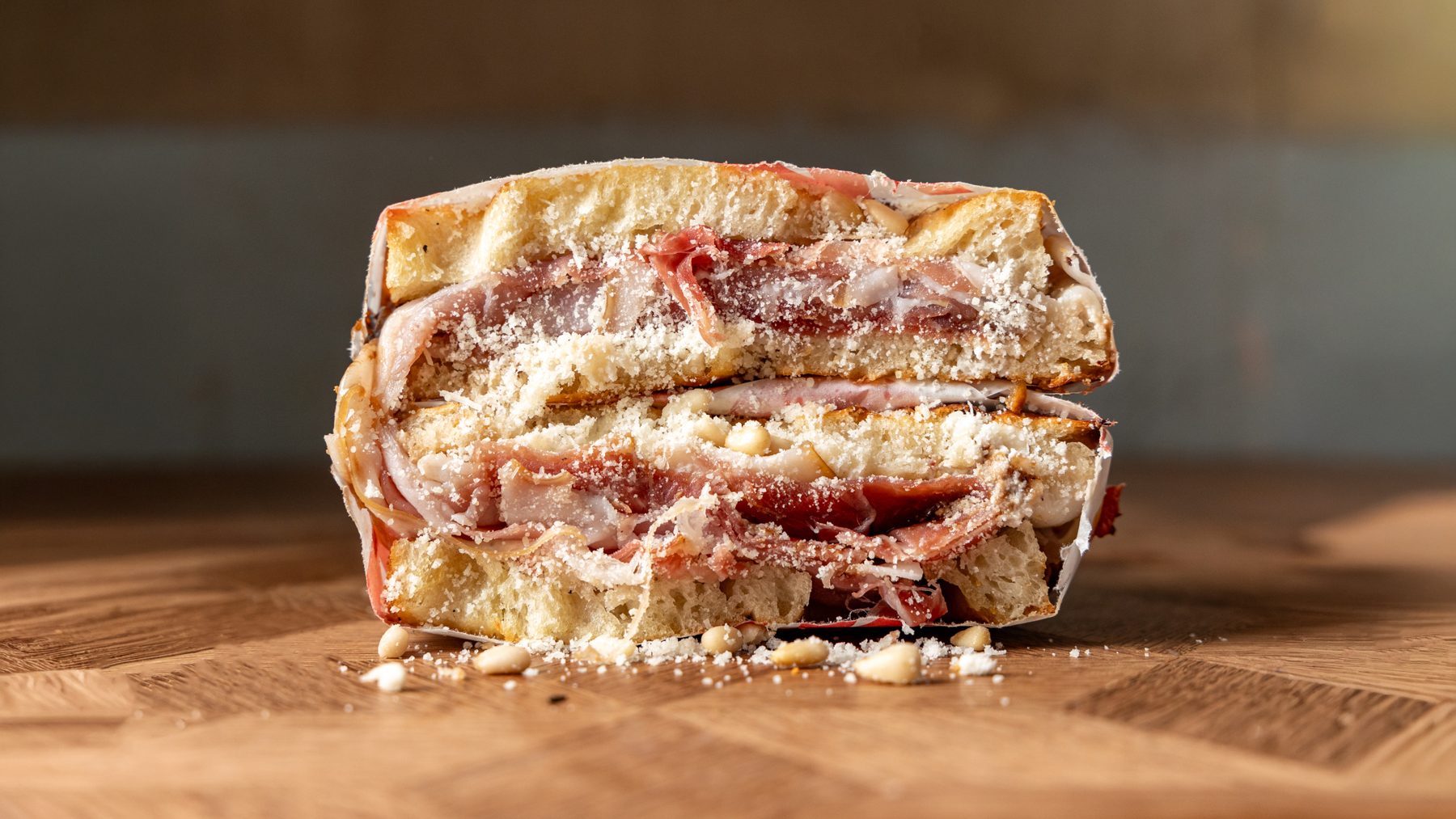 The Perfect Parma schiacciata cut in half showing prosciutto, ricotta, fig compote and toasted pine nuts on Tuscan bread