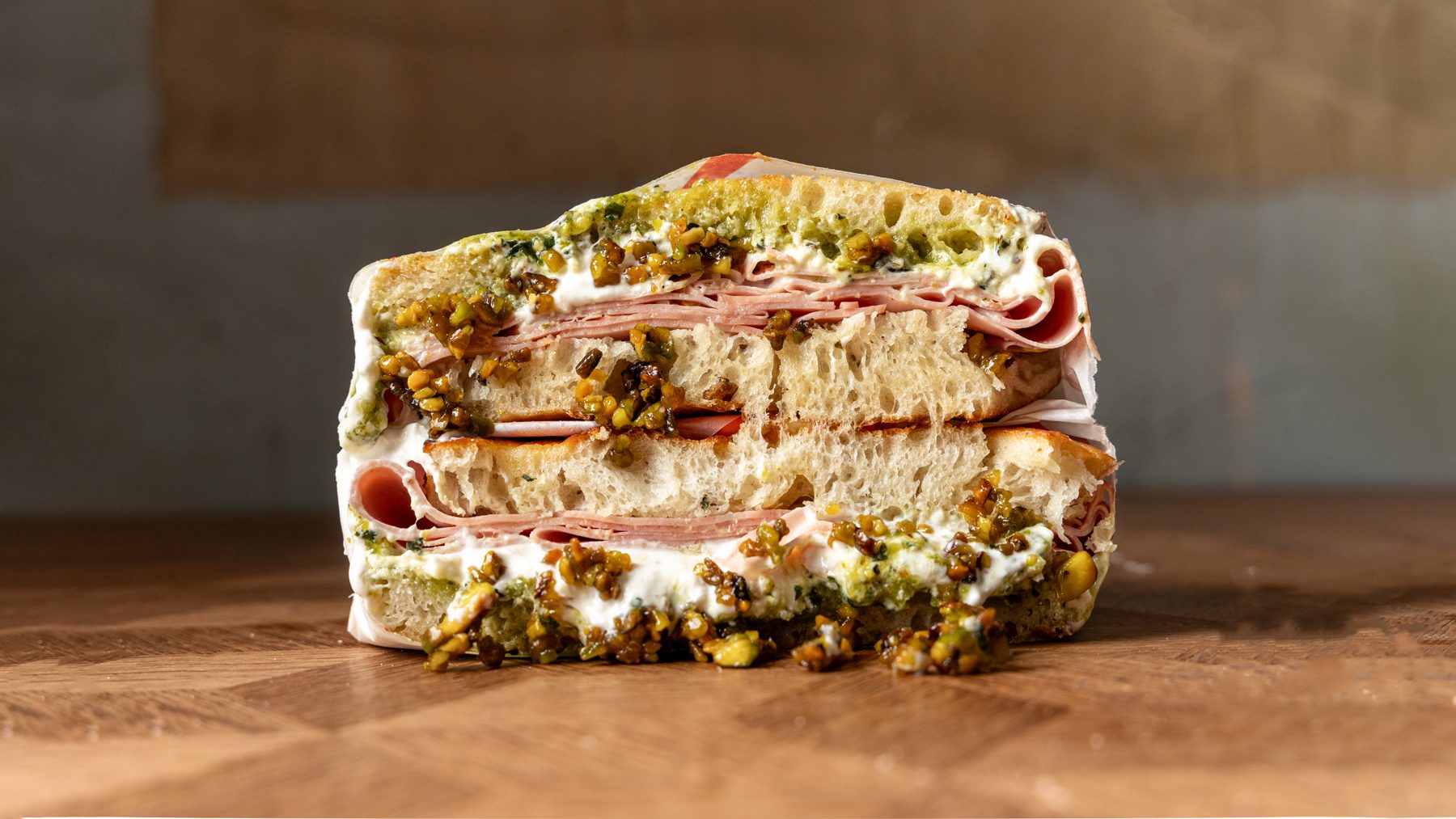 The Pronto Pistachio schiacciata cut in half showing mortadella, stracciatella and caramelised pistachios