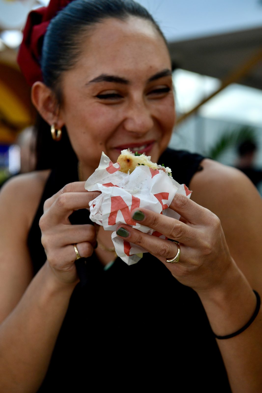Smiling guest at the Red Bull summer party enjoying a Santo Cielo schiacciata in branded wrapping