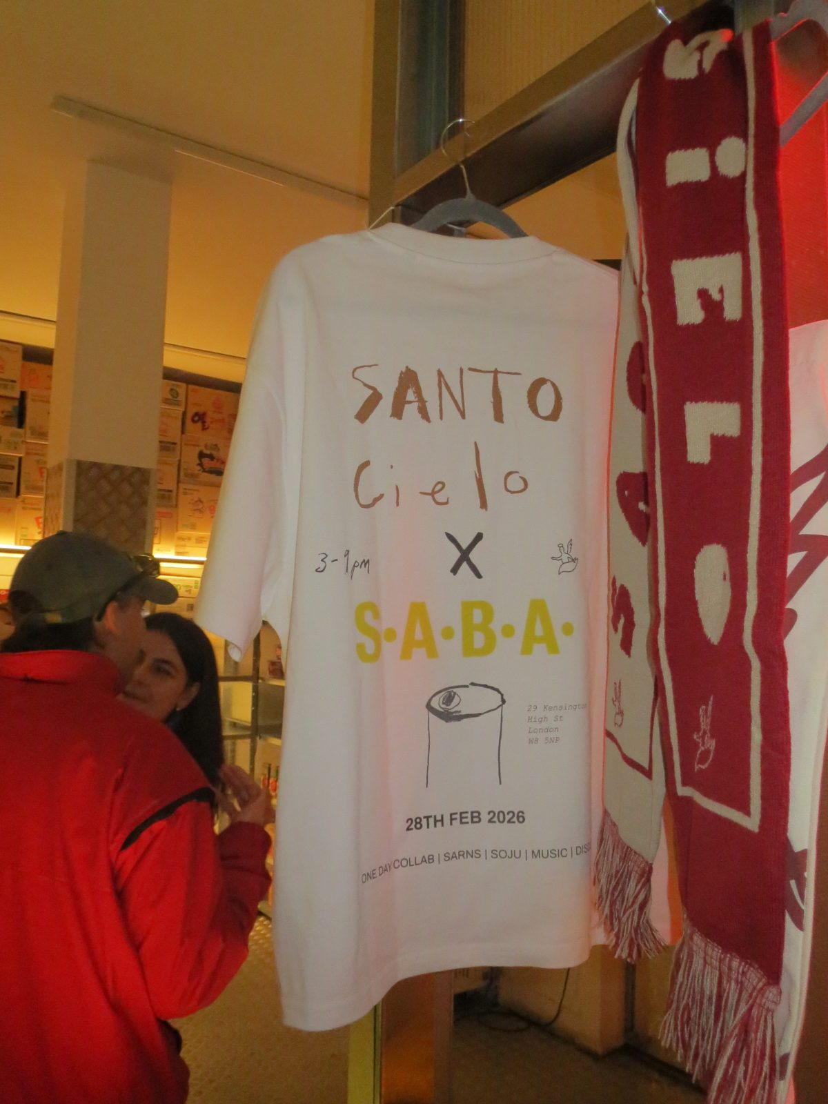 The Santo Cielo × S.A.B.A. collab tee and knitted scarf hanging at the High Street Kensington takeover