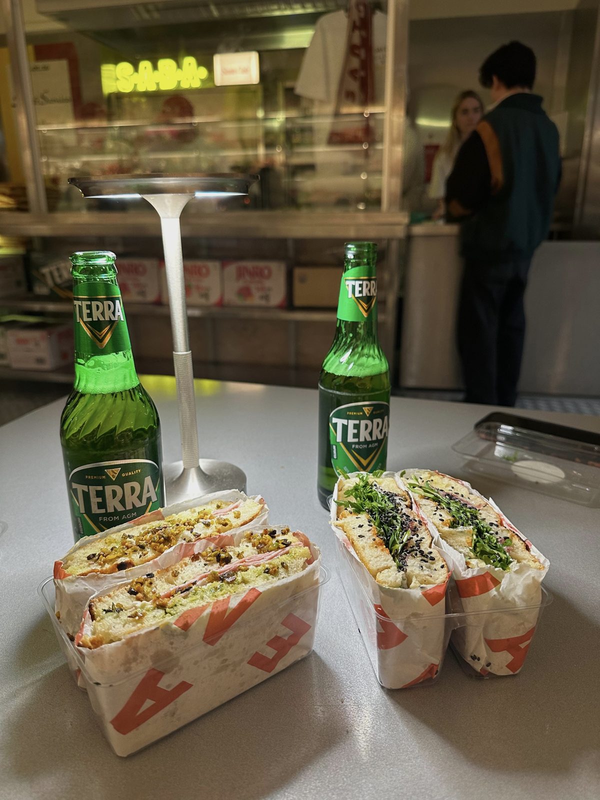 Santo Cielo × S.A.B.A. collab sandwiches served with Terra beers under the S.A.B.A. neon sign