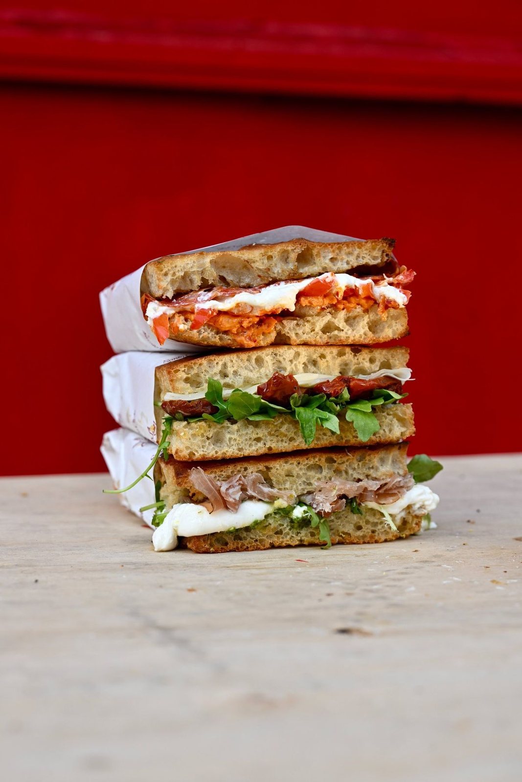 A tall stack of wrapped schiacciata sandwiches on the counter