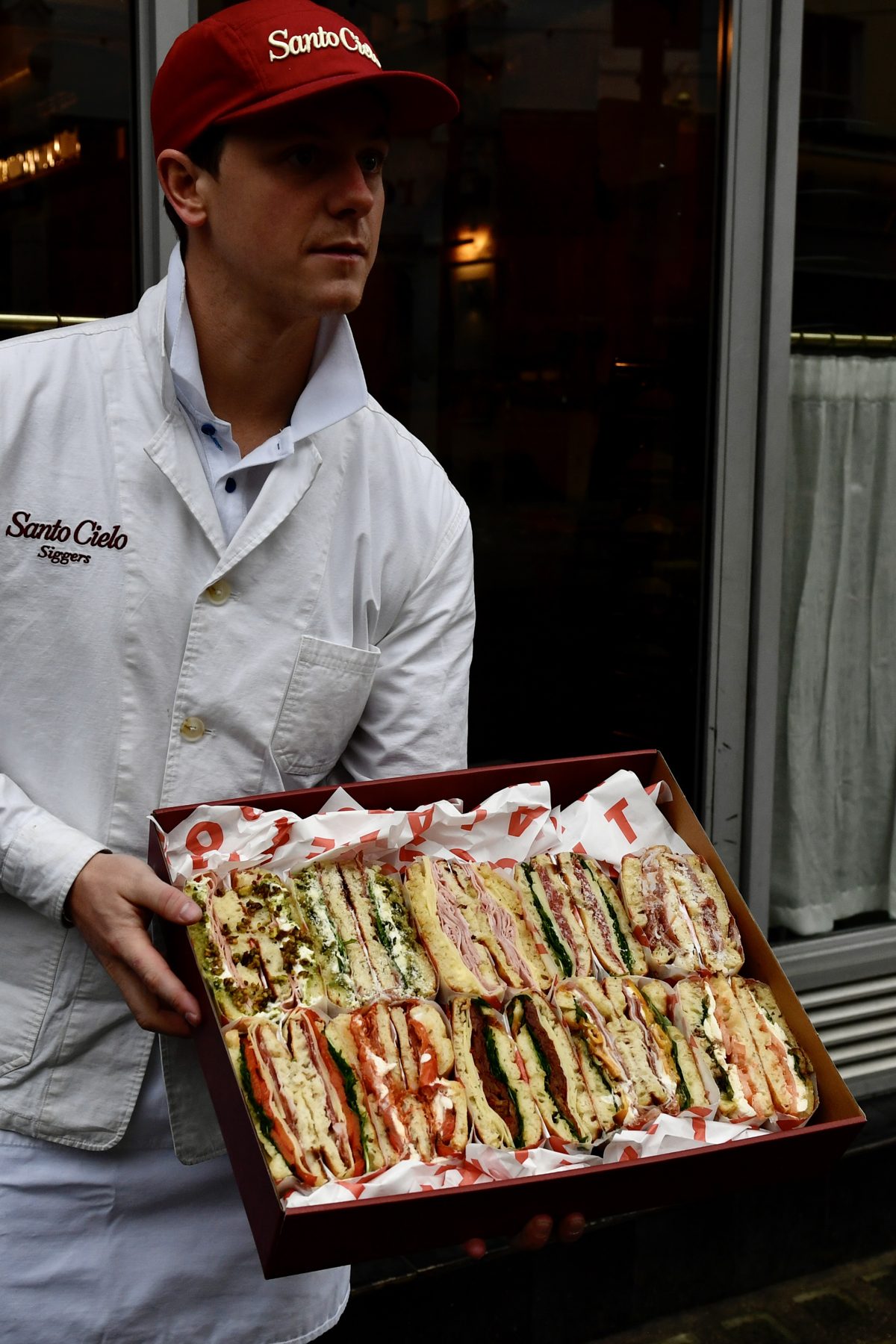 Santo Cielo team member presenting a full platter box of schiacciata sandwiches