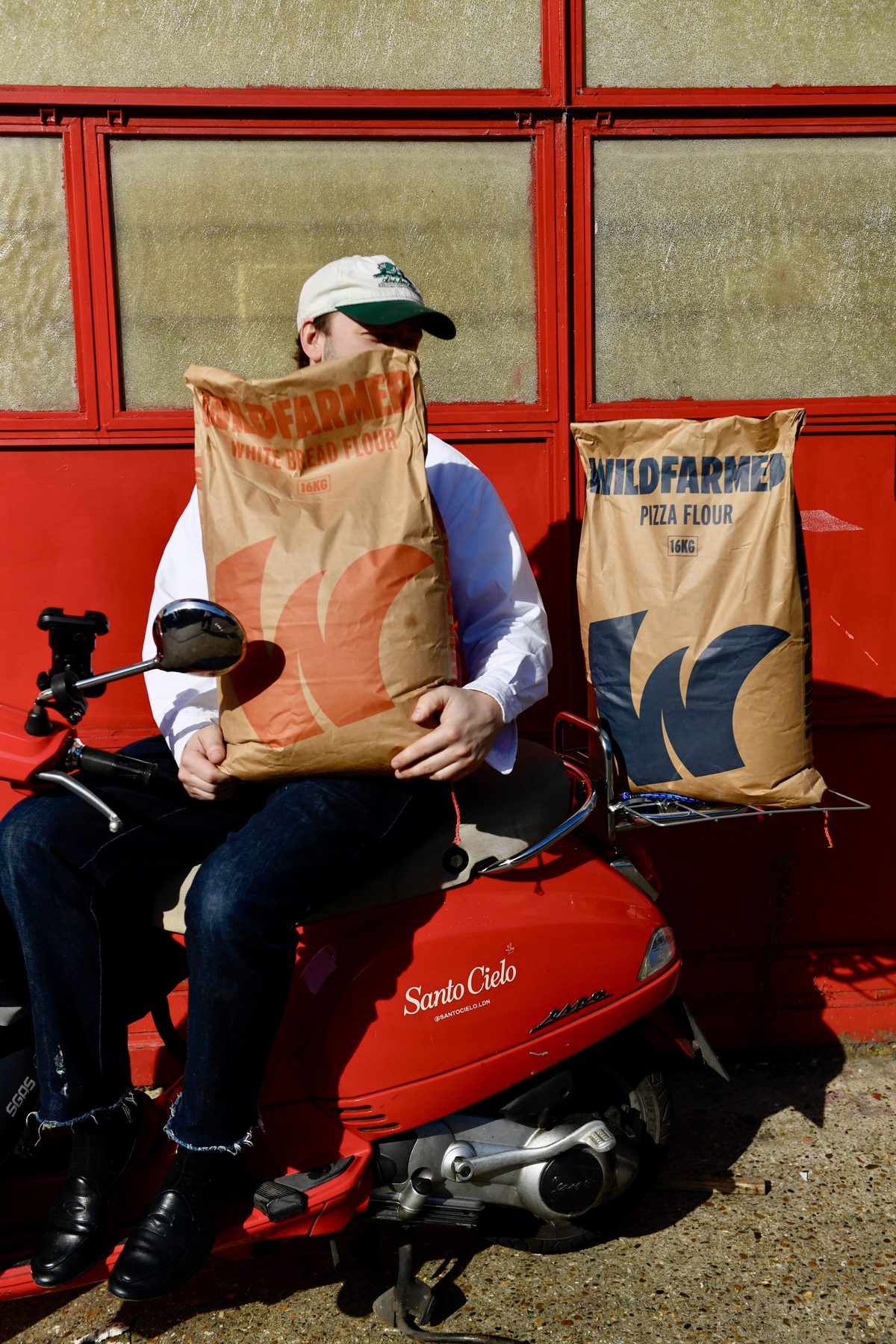 Santo Cielo baker sitting on the red delivery Vespa holding sacks of Wildfarmed bread flour