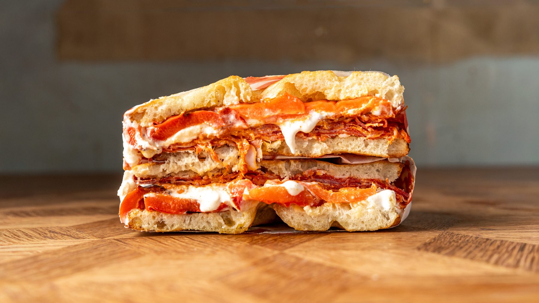 The Vesuvius schiacciata cut in half showing spicy salami, stracciatella and roasted red peppers on Tuscan bread